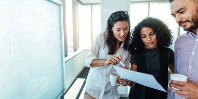 Three colleagues reviewing a document together in a bright office.