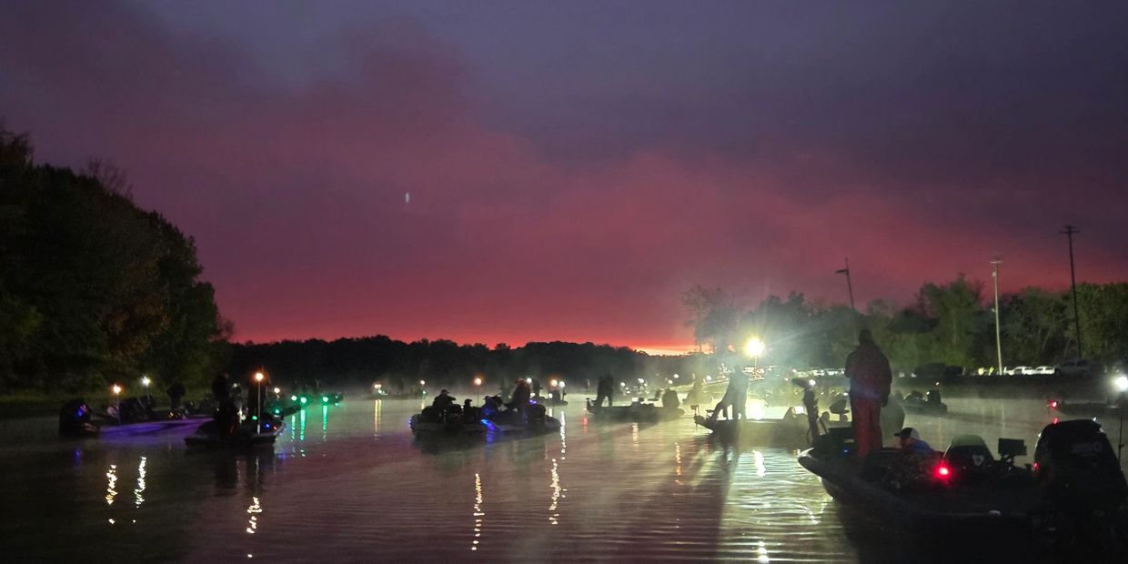 Boats on a misty river at sunrise with colorful sky.