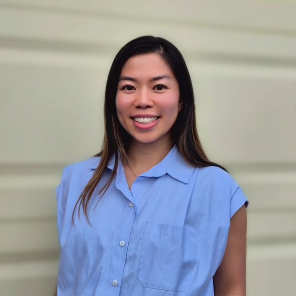 Smiling woman in light blue shirt against a neutral background.