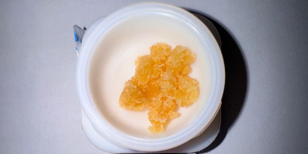 Orange crystalline substance in a white container on a gray surface.