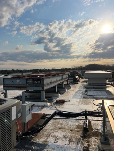 Rooftop with HVAC units under a partly cloudy sky at sunset.