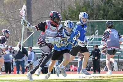 Lacrosse players in action during a competitive game on a sunny day.