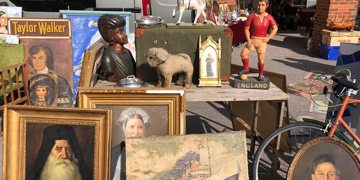 A collection of vintage paintings, sculptures, and antiques at a flea market.