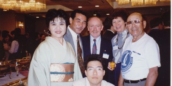 A group of six people posing happily at an indoor cultural exchange event.
