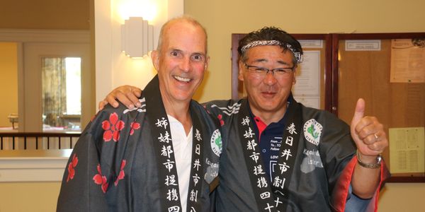 Two men in traditional Japanese attire smiling and posing together indoors.