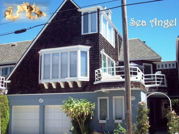 A charming seaside house named 'Sea Angel' with dark shingles and white trim.