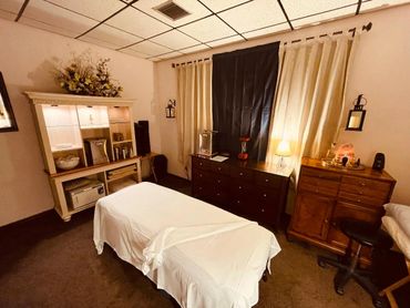 Cozy massage room with a treatment table and warm lighting.