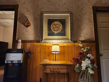 Cozy corner with a lamp, floral arrangement, and framed artwork on textured walls.