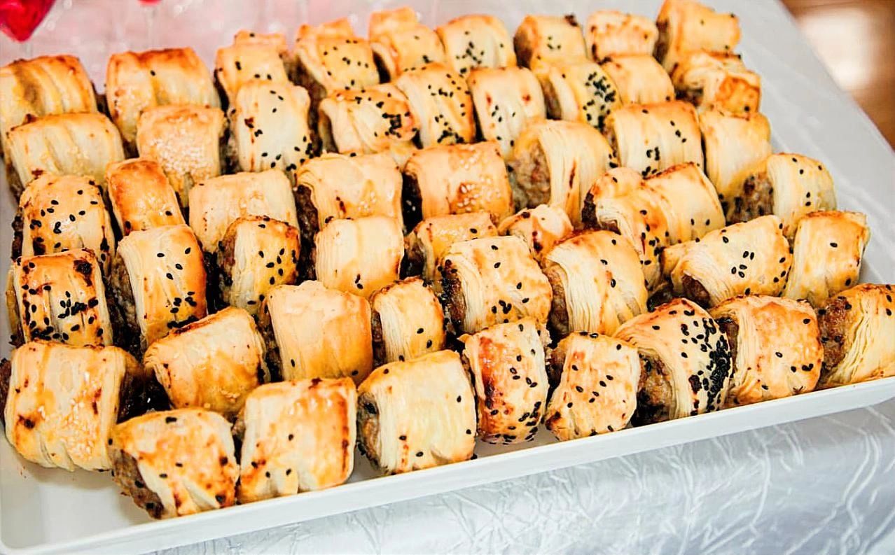 Tray of baked puff pastries with sesame seeds.