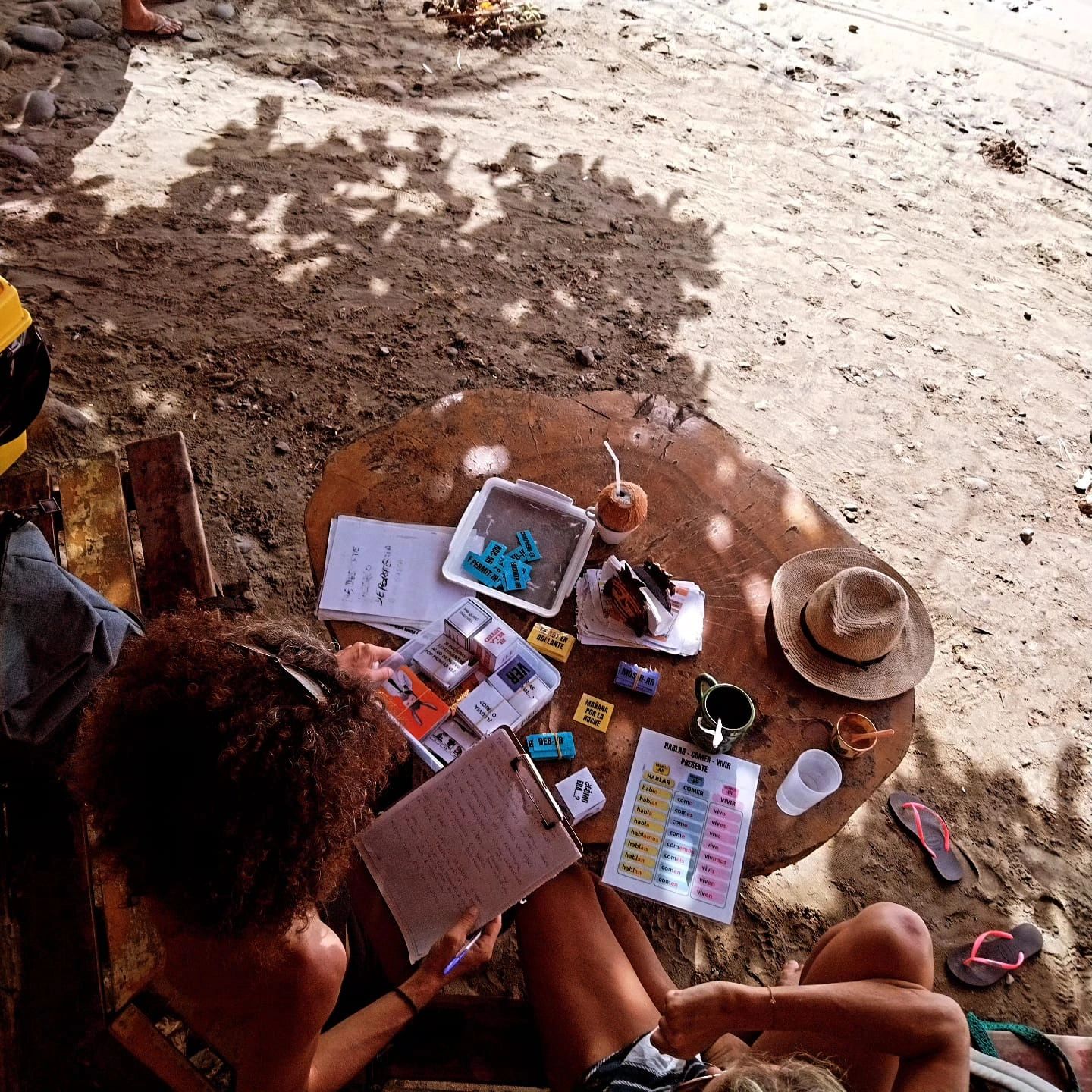 Two people studying with learning materials and notes at a rustic table.