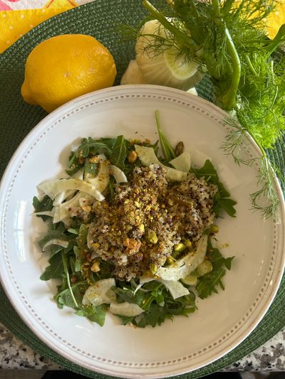 Quinoa salad with greens, fennel, and lemon on a white plate.