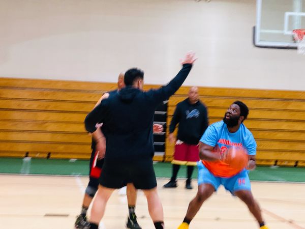 Men playing basketball in an indoor gymnasium.