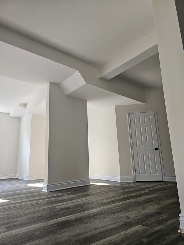 Empty room with white walls, wooden floor, and a closed white door.