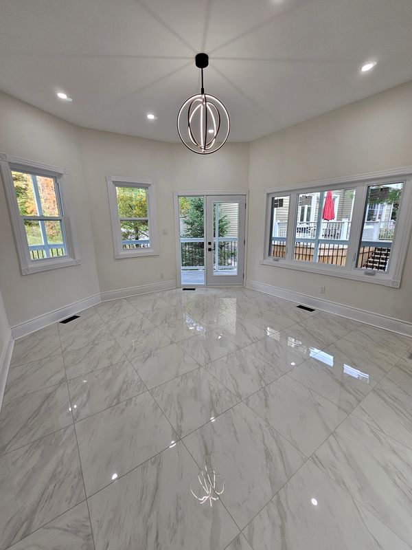 Bright empty room with large windows and modern chandelier.