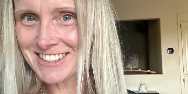 Close-up of a smiling woman with long blonde hair and blue eyes.