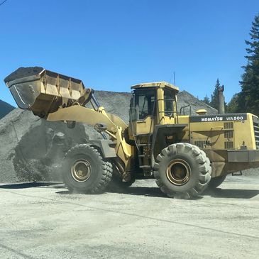 Front end loader with bucket in the air full of a scoop of gravel