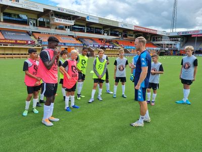Coach instructing young soccer players on a field during practice.