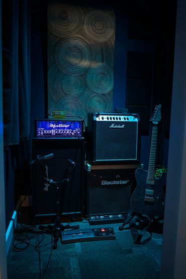 A dark room with musical amplifiers and an electric guitar.