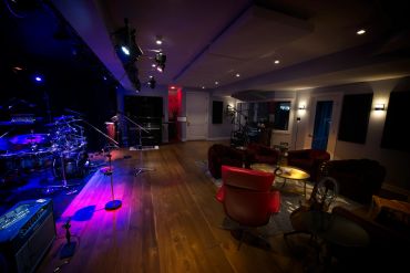 Cozy music studio with instruments and seating.