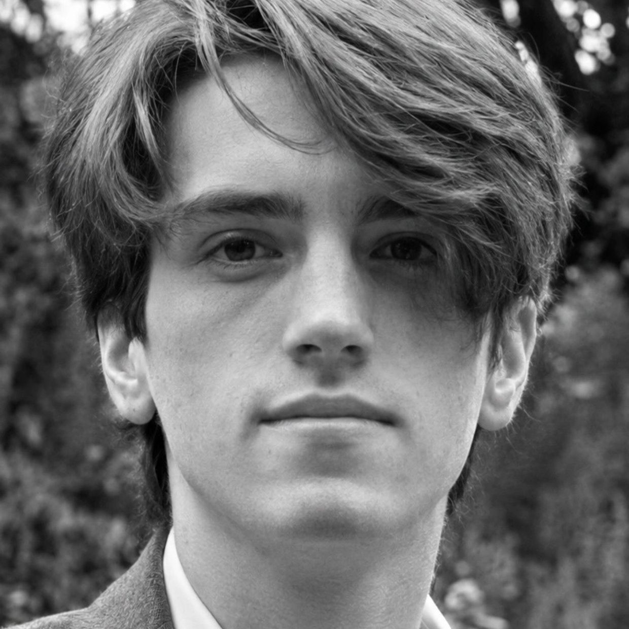 Black and white close-up of a young man with tousled hair.