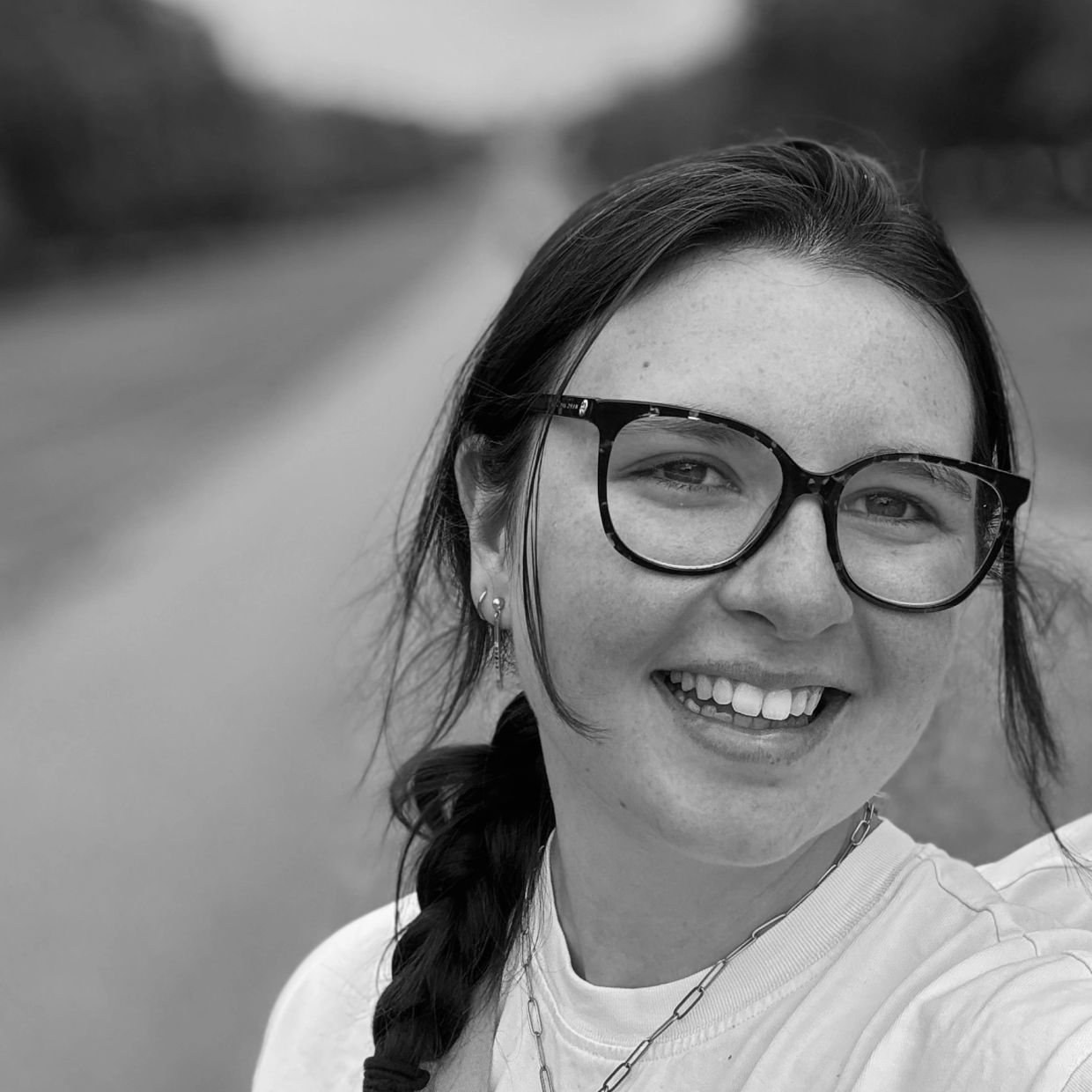 A smiling woman with glasses in a black and white photo.