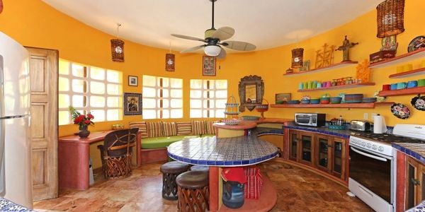Bright yellow kitchen with curved seating and a tiled round table.