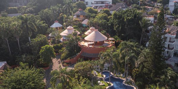 Lush tropical resort with round pavilion and pool surrounded by greenery.