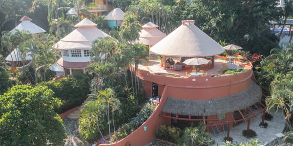 A tropical resort with round huts and lush greenery.