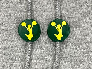 Silhouetted cheerleader charm in dark green and gold on sweatshirt drawstring.