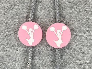 Silhouetted cheerleader charm in pink and white on sweatshirt drawstring.