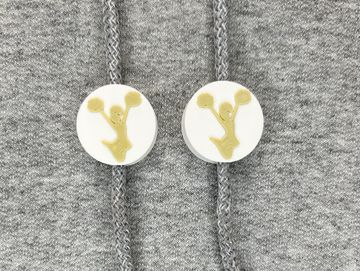 Silhouetted cheerleader charm in white and vegas gold on sweatshirt drawstring.