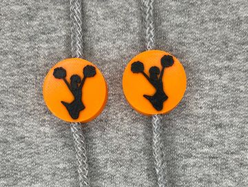 Silhouetted cheerleader charm in orange and black on sweatshirt drawstring.