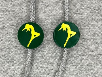 Silhouetted dance charm in dark green and gold on sweatshirt drawstring.
