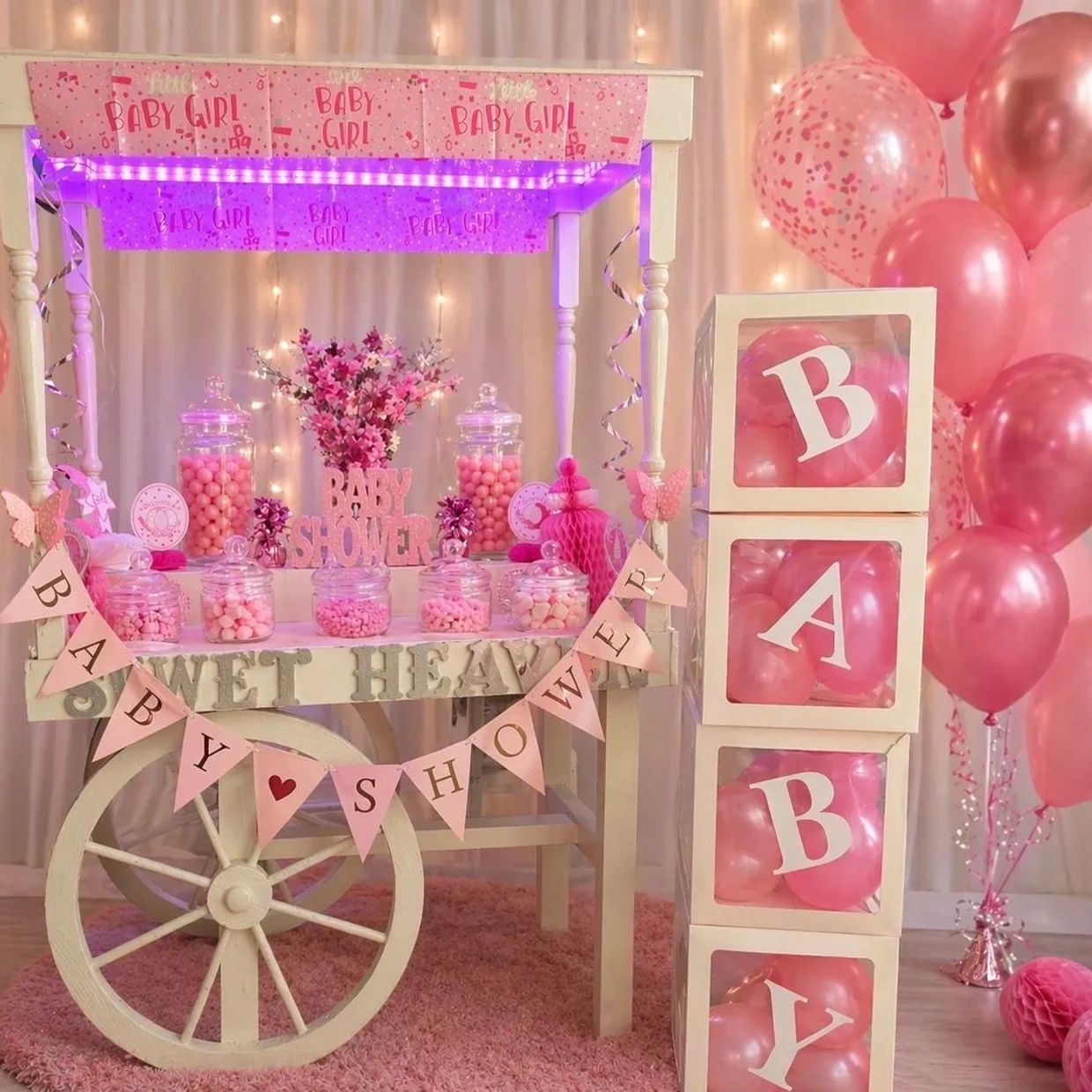Pink-themed baby shower setup with candies, balloons, and decorations.