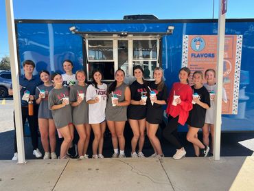 Group of young people enjoying shaved ice treats outside a blue food truck.