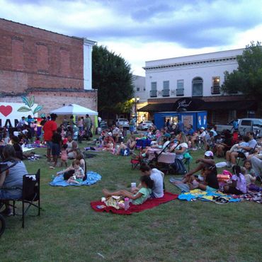 People gather on blankets and chairs in a community park as evening approaches.