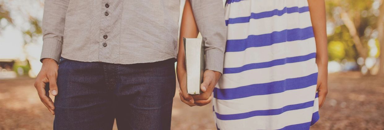 A Man and a woman holding hands and a bible 