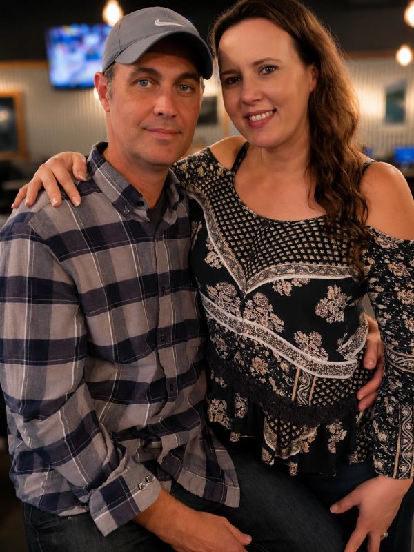A couple smiling, sitting close together indoors.
