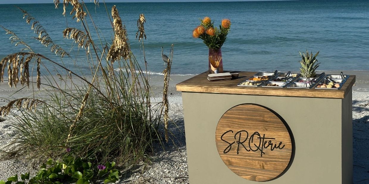 A beachside snack bar with fresh toppings and flowers under a clear blue sky.