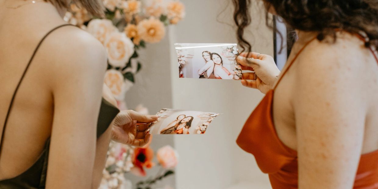 Two women holding photos of themselves at an event.