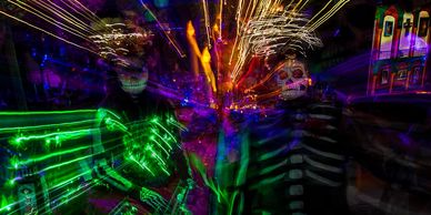 Two people in glow-in-the-dark skeleton costumes with light trails.