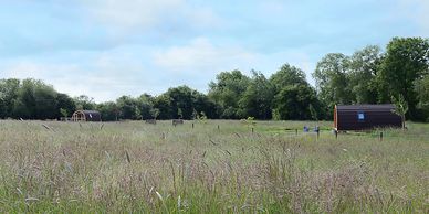A view across the meadow at the two glamping pods - dog friendly glamping holidays