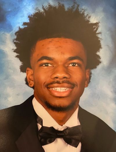 Young man in formal attire with a bow tie smiles against a blue backdrop.