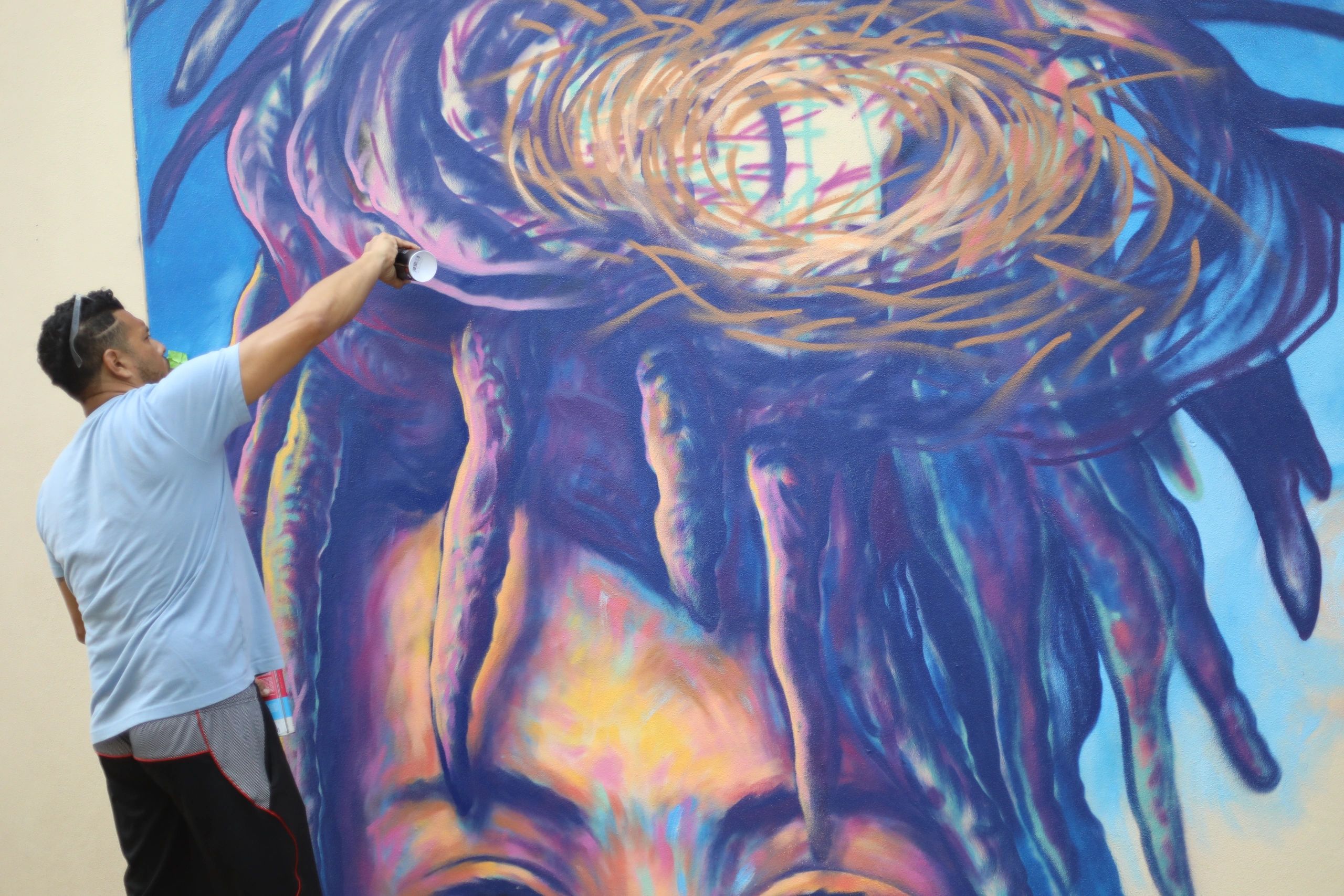 Artist spray painting a colorful mural on a wall.