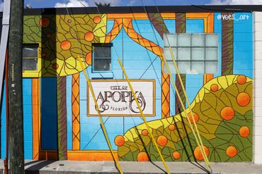 Colorful mural on a building wall in Apopka, Florida, featuring abstract shapes and trees.