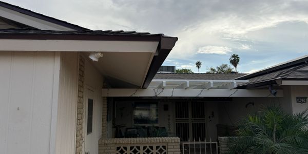 Residential house exterior with cloudy sky and palm trees.