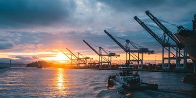 A boat passing some oil rigs in front of a sunset.