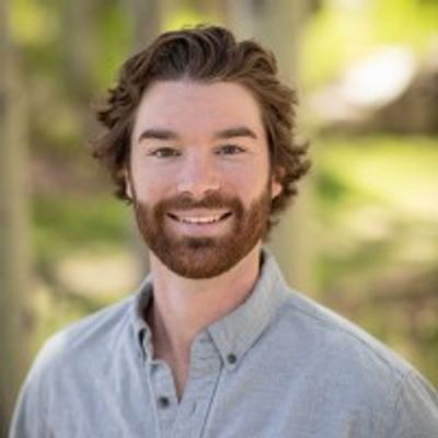 Smiling man with beard outdoors.