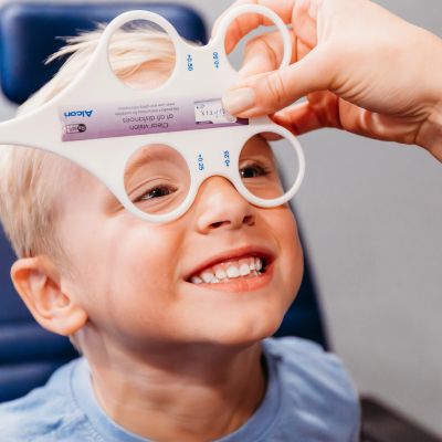 Happy child undergoing vision test with trial frame.