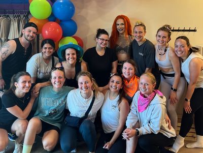 Group of people smiling indoors with colorful balloons.
